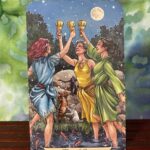 Tarot Card the Three of Cups, depicting three women dancing in celebration