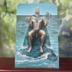 The tarot card King of Cups is represented by a naked man sitting on a rock in the middle of the sea