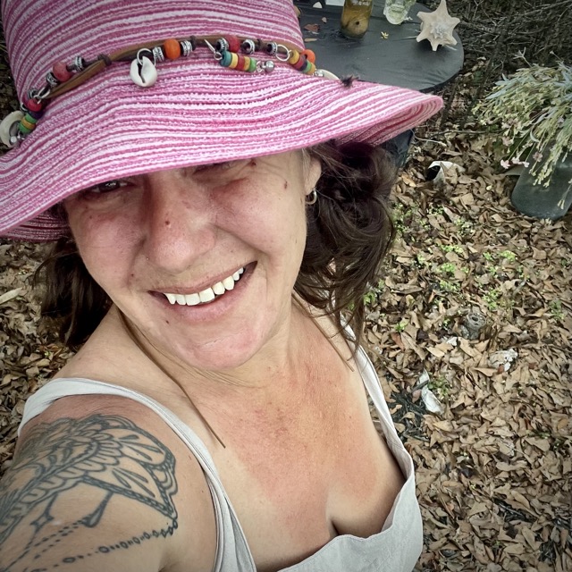 The Old Town Witch, wearing a pink hat and a grey apron, enjoying the peace and quiet of her woods.